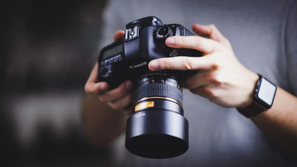 Vollformat-Kamera vs. Crop-Sensor – Unterschiede erklärt Person hält eine Canon DSLR-Kamera – Fokus: Vollformat-Kamera vs. Crop-Sensor