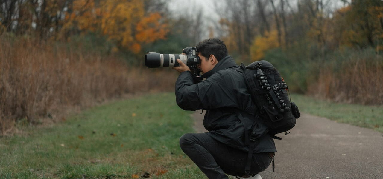 Fotograf blickt durch den optischen Sucher einer Spiegelreflexkamera im Wald.