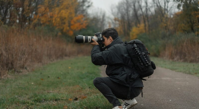 Vorteile einer Spiegelreflexkamera: Lohnt sich der Kauf einer DSLR auch 2026 noch? 2 Fotograf blickt durch den optischen Sucher einer Spiegelreflexkamera im Wald.