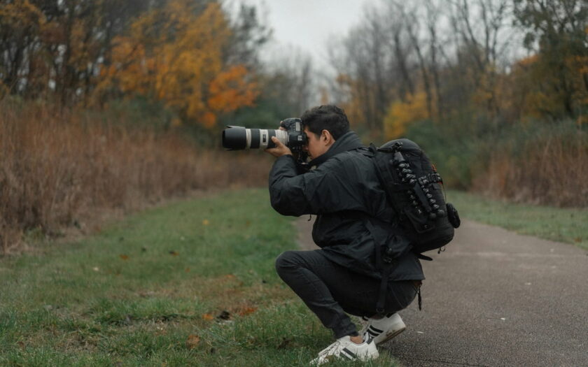 Fotograf blickt durch den optischen Sucher einer Spiegelreflexkamera im Wald.