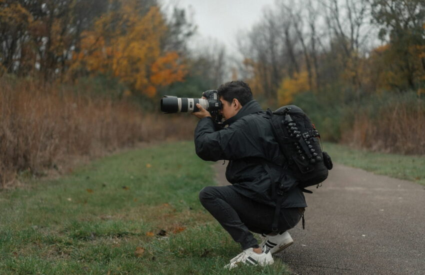Fotograf blickt durch den optischen Sucher einer Spiegelreflexkamera im Wald.