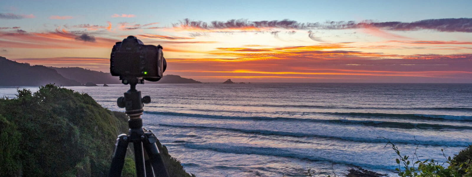 Kamera auf Stativ bei Sonnenuntergang an der Küste für Landschaftsfotografie