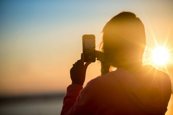 Sonnenuntergang mit Smartphone fotografieren Frau fotografiert Sonnenuntergang mit Smartphone