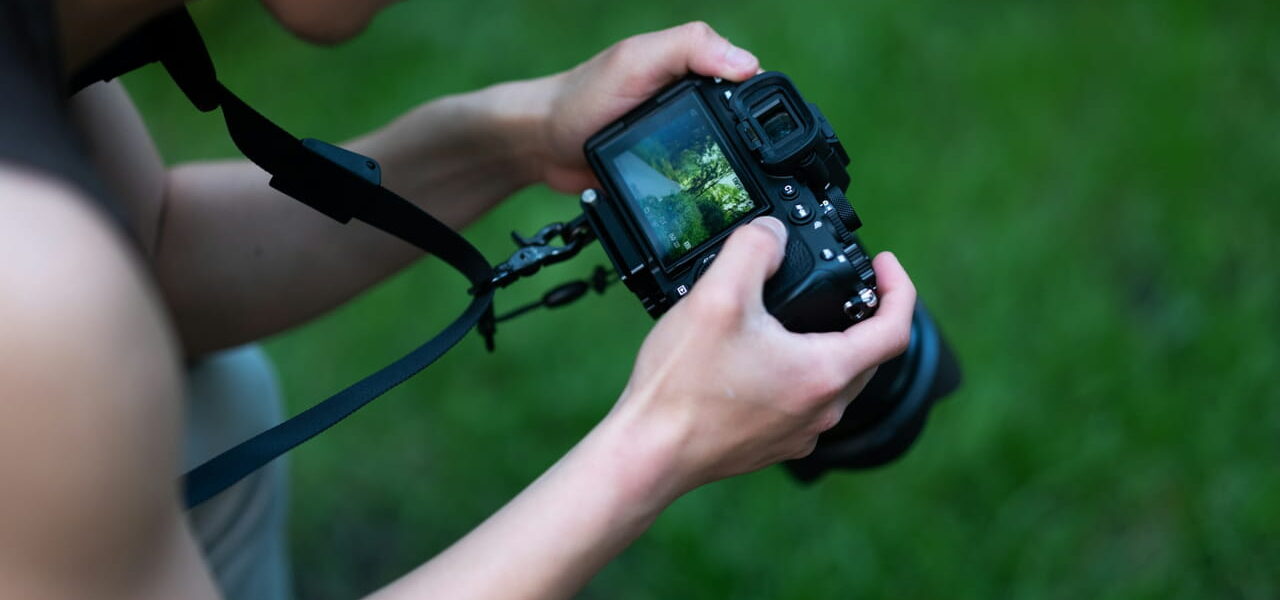 Fotograf mit DSLR-Kamera und Kameragurt in der Natur