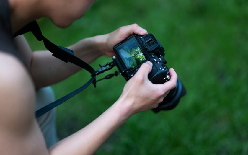 Fotograf mit DSLR-Kamera und Kameragurt in der Natur