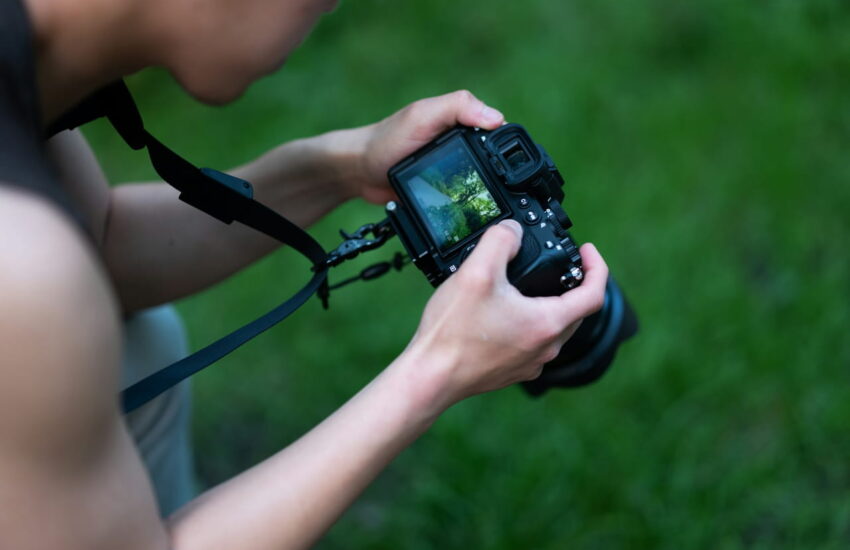 Fotograf mit DSLR-Kamera und Kameragurt in der Natur