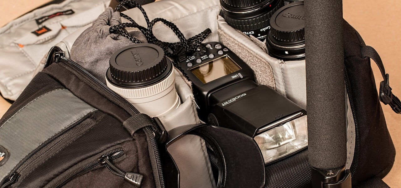 Geöffnete Fototasche mit Kamera, Objektiven, Blitzgerät und Zubehör wie Stativ und Filtereinsätzen – unverzichtbare Gadgets für deine Fototasche.