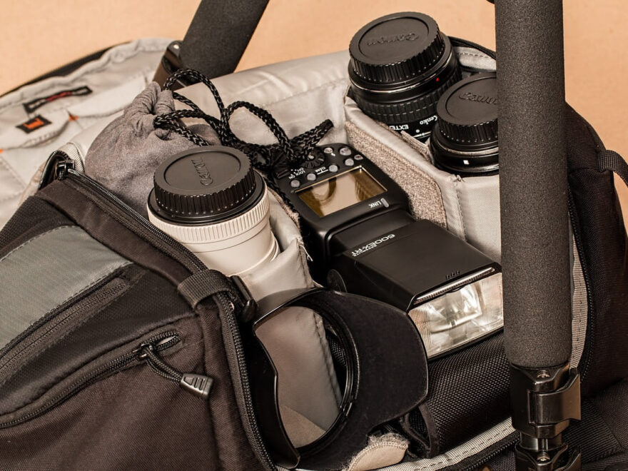 Geöffnete Fototasche mit Kamera, Objektiven, Blitzgerät und Zubehör wie Stativ und Filtereinsätzen – unverzichtbare Gadgets für deine Fototasche.