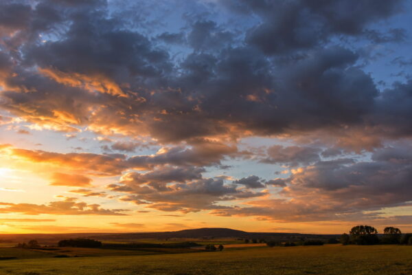 Wolken im Abendlicht fotografieren Wolken im warmen Abendlicht über einer weiten Landschaft