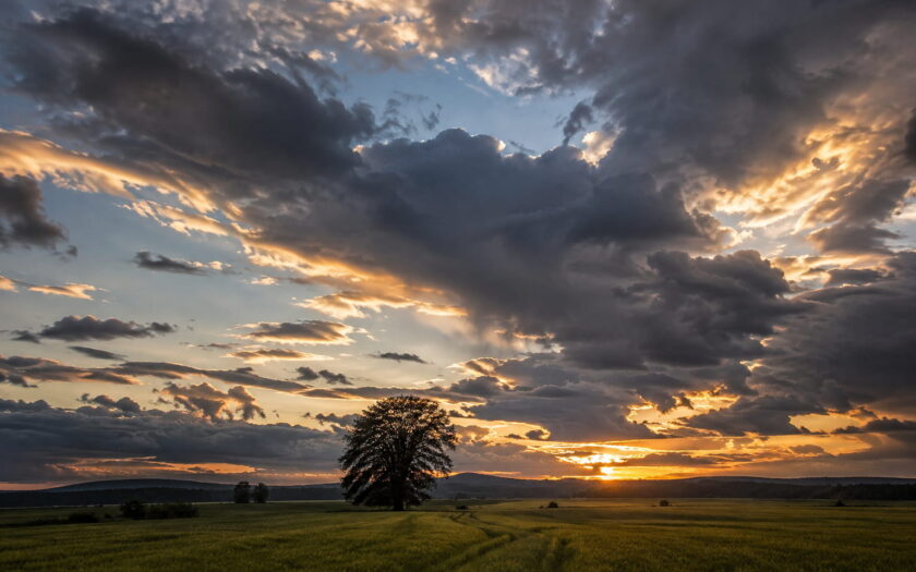Wolken fotografieren über einer Landschaft bei Sonnenuntergang