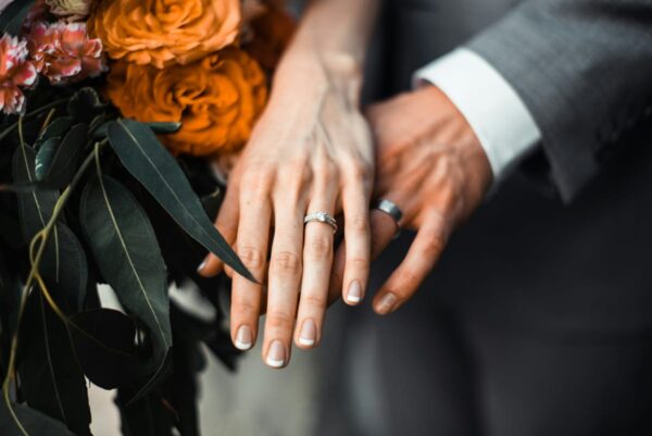 Hochzeitsfotografie mit Fokus auf Eheringe und Brautstrauß am Hochzeitstag