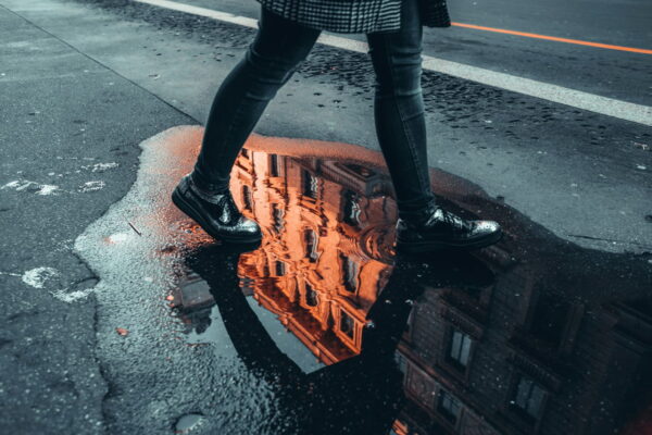 Spiegelung eines Gebäudes in einer Pfütze als kreatives Reisefotografie-Motiv