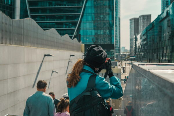 Eine Fotografin mit Rucksack fotografiert moderne Architektur in einer Stadt.